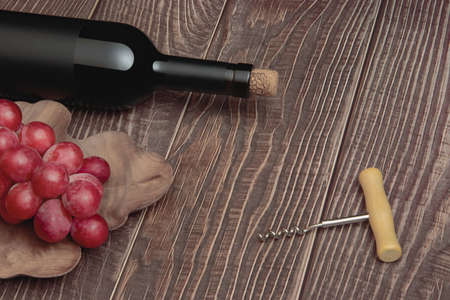 Expensive wine bottle with corkscrew and grapes on conceptual wooden boards backgroundの写真素材