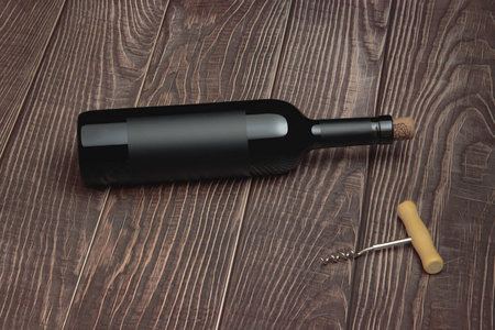 Wine bottle with vintage label and corkscrew on wooden table top backgroundの写真素材