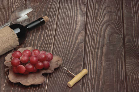 Expensive wine bottle with corkscrew and grapes on conceptual wooden boards backgroundの写真素材
