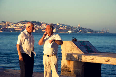 Two old Portuguese men talking while standing on a pier on river Tejo, Lisboaのeditorial素材