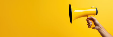 Generative AI, megaphone in hand on an empty yellow background, panoramic image with copy spaceの素材