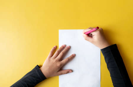 a child draws on the yellow table. Top view