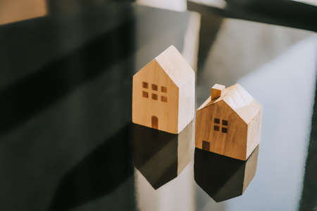 Two Wooden model houses on reflecting surface. House choosing concept.の写真素材