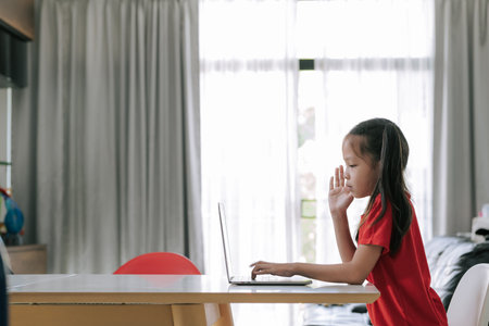 Asian girl raise her hand during online class to ask question. Stay home during pandemic.の写真素材