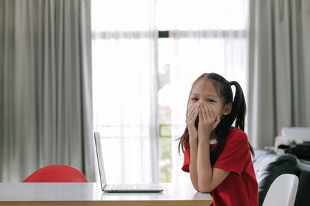 Asian girl cover her mouth with both hands as she answered the question wrong while study online.