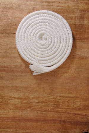 Rolled-up white rope on wood background.の写真素材