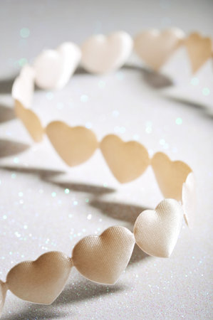 chain of white-yellow textilehearts on silver sparkle background