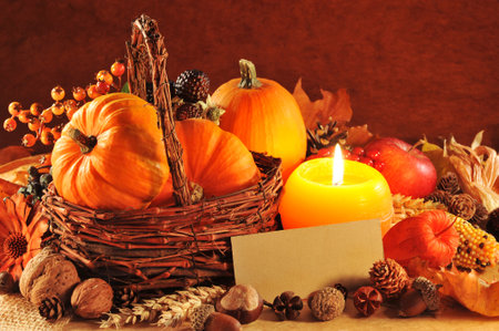 Thanksgiving - different pumpkins, nuts, maize cob and apple in rattan basket with candlelight and...