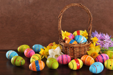 many painted easter eggs with easter basket and hyacinth in front of brown background