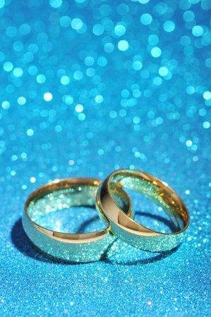 Two golden rings on turquoise glitter backgroundの写真素材