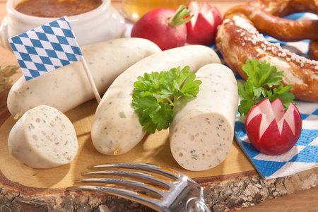 Bavarian veal sausage breakfast with sausages, wheat beer, soft pretzel and mild mustard on dark weathered wooden boardの写真素材