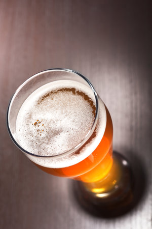 macro view of a beer glass with froth on the tableの写真素材