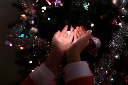 Close-up of child's hands illuminated by the Christmas tree lights.