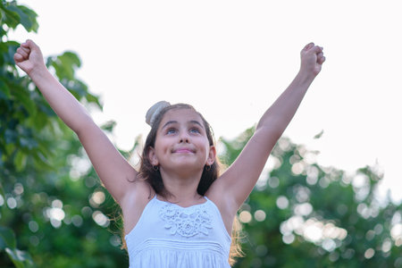 Victorious girl celebrating with her arms in the air. Success, achievement and victory concept.