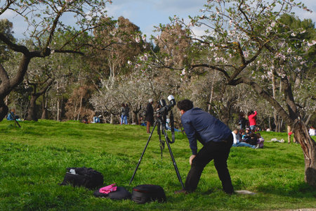 Madrid, Spain - February 28, 2021: male photographer filming almond tree bloom in the crowded park during covid restrictionsのeditorial素材