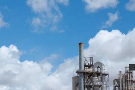Metallic pipes against vivid blue sky with clouds. Industrial background. Concepts of global warming and pollutionの写真素材