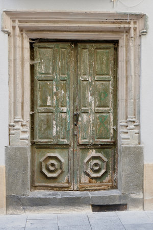 Vertical photo of aged nostalgic front door with paint scratches. Conceptual term of time journey, nostalgia and travel to past. Jaca, Huesca, Aragon / Spainの写真素材