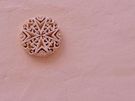 Detailed stucco heraldic emblem of Malta on rough painted wall of pastel colour. Maltese cross ornamentの写真素材