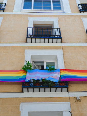 Striped flags of gay and lesbian communities hang outside the windows meant to support lgbt people. Vertical photo.の写真素材