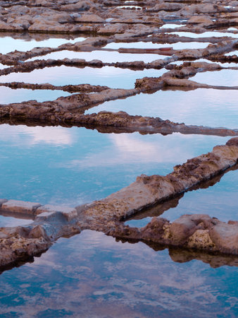 Salt making pans with water of rare colour in Gozo island, Malta at sunset time. Ancient salt production process by evaporation.の写真素材
