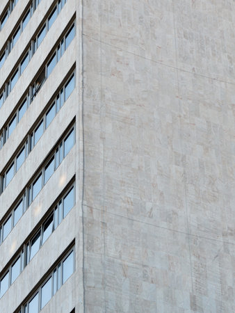 Corner on gray facade with lines of windows in 70s style from outside in Madrid, Spain.