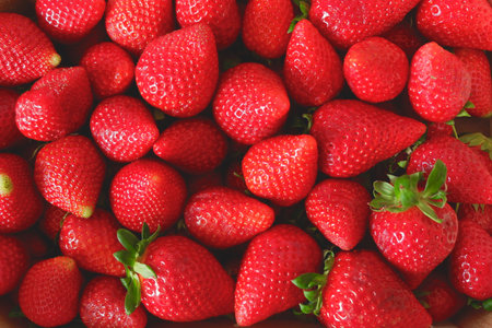 Many strawberries of faded red color and different sizes on the local farmer market in Spain