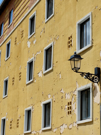 Weathered facade with peeling yellow paint in the old center of Segovia, Spain.の写真素材