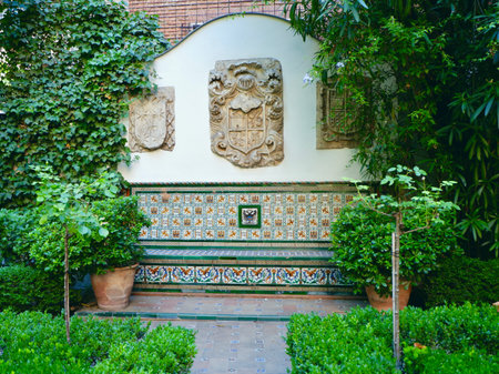 Traditional Spanish garden with tiled bench and vivid green plants growing around in Madrid, Spain.の写真素材