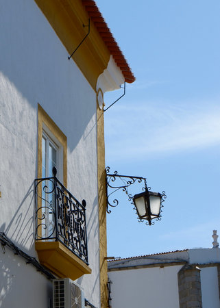 Vintage street lamp made of black metal hang on the corner of rural Portuguese house in the village in Portugal.の写真素材