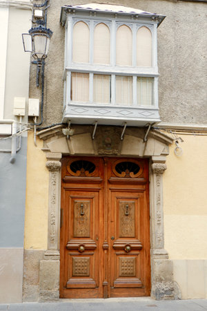 Retro wooden door with floral ornate and balcony on top in Jaca, Aragon, Spain. vertical pictureの写真素材