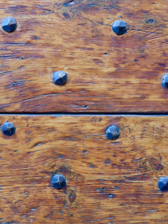 Close up of old wooden hutch surface details. Two planks of aged brown lacquered wood with decorative metal elements of pyramidal shape. Vertical photos.の写真素材