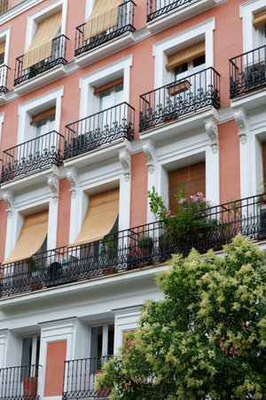 The striking facade showcases an ornate design with vibrant colors, laced with lush plants on balconies. Sunlight enhances the appeal of the architecture.の写真素材