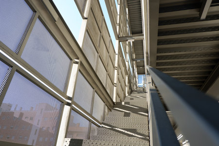 The photograph showcases a contemporary staircase featuring sleek metal railings and surfaces, illuminated by natural light. The design highlights safety and style.の写真素材