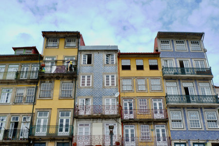 The row of colorful buildings in Porto illustrates the rich architectural heritage of the city. Balconies adorned with iron railings and patterned tiles add to the charm.の写真素材