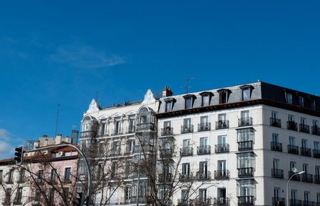 Beautiful historic architecture showcases charming balconies against a bright blue sky in a lively urban part of Madrid during a winter day.の写真素材