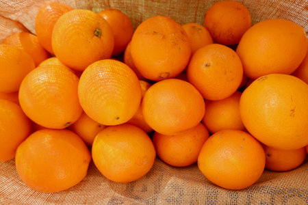 A vibrant display of fresh oranges fills a woven basket, showcasing their bright orange color. This scene captures the essence of a morning visit to a local market.の写真素材