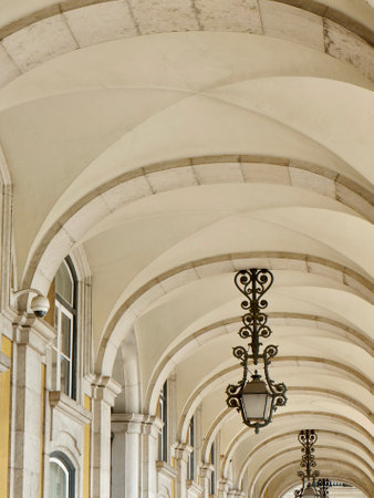 Intricate arches and vintage lanterns create a charming atmosphere beneath a historic structure in a lively urban square, showcasing architectural beauty and detail.の写真素材
