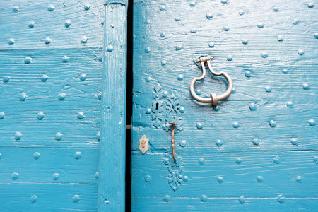 Bright blue door with a textured surface and intricate designs showcases a vintage door knocker, inviting curiosity and admiration from passersby in a quaint neighborhood.の写真素材