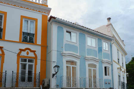 Colorful buildings line a quiet street in a coastal town. The blue and white facades reflect the serene atmosphere as the sun sets in the distance.の写真素材
