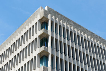 A striking building showcases innovative design with sharp angles and unique textures under a clear blue sky. Sunlight reflects off the structure's surfaces, enhancing its beauty.の写真素材