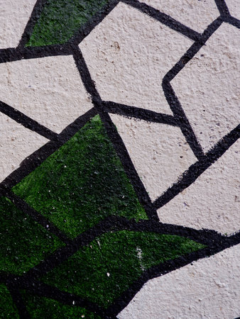 A detailed view of a mural showcasing a green and white plant design on a textured wall. This street...