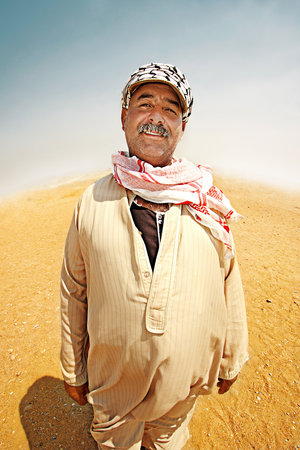 in Egypt the smiling Bedouin with mustache in a pink scarf stands in the desertのeditorial素材