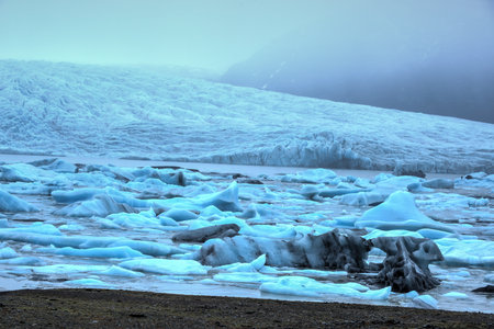 View of Fjallsarlon Glacial lake full of floating icebergs near the Fjallsjokull glacier on a cloudy...