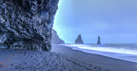 Wide view of Reynisdrangar rock formations on Reynisfjara Beach at dusk, Halsanefhellir, Iceland 