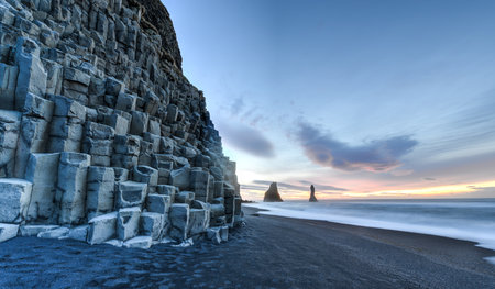 Wide view of Reynisdrangar rock formations on Reynisfjara Beach at sunrise, Halsanefhellir, Iceland 
