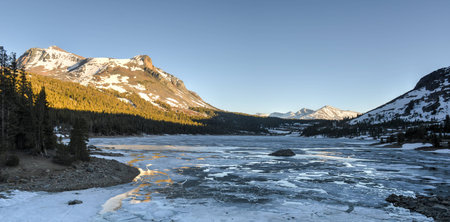 Tioga Lake at sunset. Thawing high-mountain lake in Yosemite National Park along Tioga Road during...
