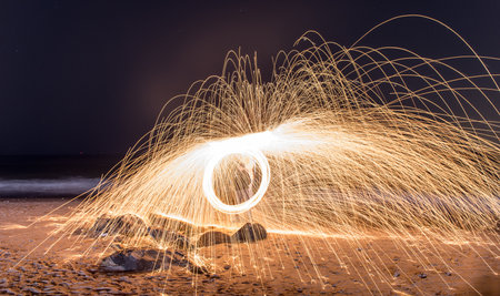 Showers of hot glowing sparks from spinning steel wool at Coney Island Beach, Brooklyn, New York.