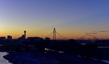 Downtown Dallas skyline with the Margaret Hunt Hill Bridge at sunrise in Texas, USA from the Trinity River.の写真素材