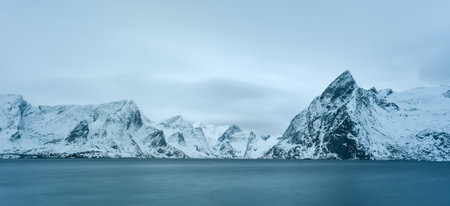 Fishing hut (rorbu) in the Hamnoy and Lilandstinden mountain peak in winter in Reine, Lofoten Islands, Norway.の写真素材