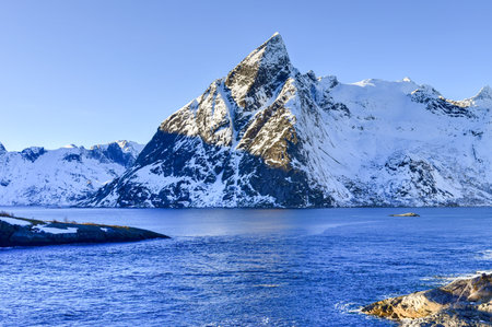 Fishing hut (rorbu) in the Hamnoy and Lilandstinden mountain peak in winter in Reine, Lofoten...